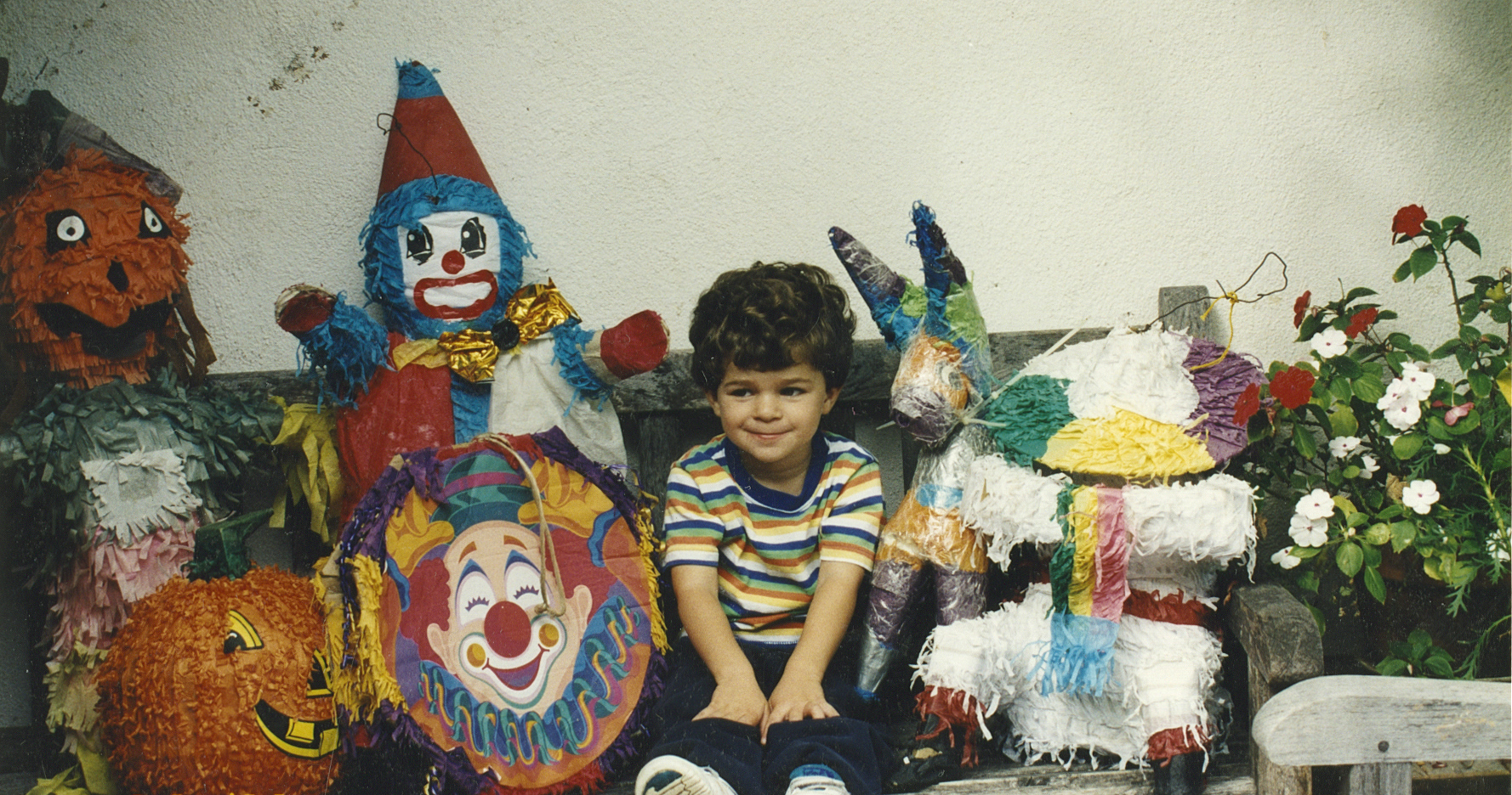 child sitting surrounded by pinatas