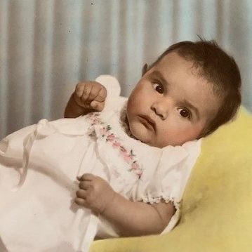retro color photo of baby in formal pink dress lying down