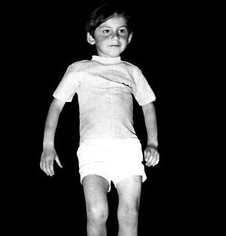 black and white photo of child in shorts getting ready to swim