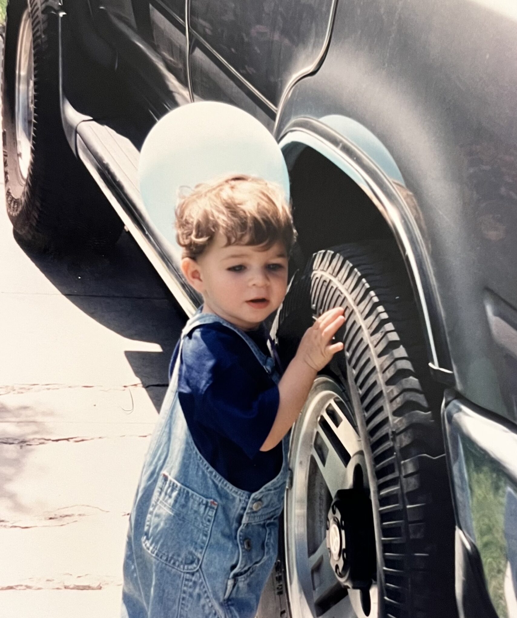 baby boy standing next to a car with a balloon